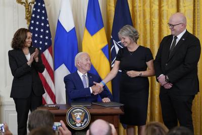 President Joe Biden shakes hands with Karin Olofsdotter, Sweden's ambassador to the U.S., as Mikko Hautala, Finland's ambassador to the U.S., looks on at the signing ceremony in the East Room of the White House on Tuesday.