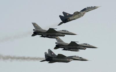 Polish Air Force, Russian-made MiG-29's fly above and below Polish Air Force, U.S.-made, F-16 fighter jets during an air show.
