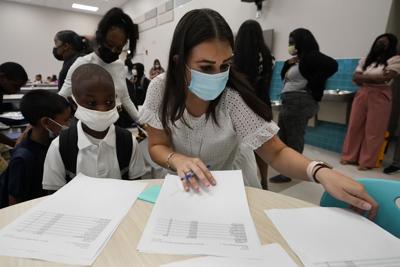 School psychologist Megan Hahn, center, helps students find their classrooms during the first day of school at Washington Elementary School in Riviera Beach, Fla.