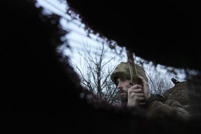 A Ukrainian service member listens to artillery shots standing in a trench on a position at the line of separation between Ukraine-held territory and rebel-held territory near Zolote, Ukraine, late Saturday, Feb. 19, 2022.