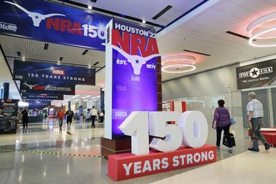 Convention attendants walk past some of the signage in the hallways outside of the exhibit halls at the NRA Annual Meeting held at the George R. Brown Convention Center on May 26, 2022, in Houston.