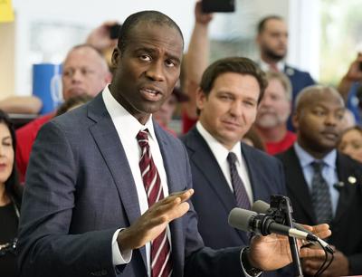 Florida Surgeon General Joseph Ladapo, front left, gestures as speaks to supporters and members of the media before a bill signing by Gov. Ron DeSantis, Nov. 18, 2021, in Brandon, Fla.