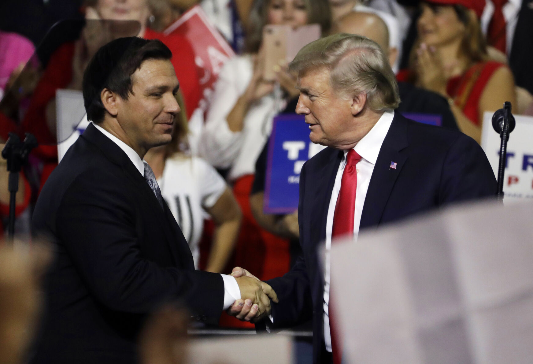 Former President Donald Trump shakes hands with Florida Gov. Ron DeSantis during a rally in Tampa, Fla., Tuesday, Aug. 28, 2018.