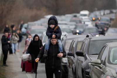 Ukrainian refugees walk beside vehicles lining up to cross into Moldova at the Mayaky-Udobne crossing point on Feb. 26.