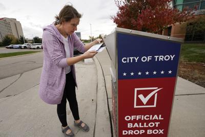 Nikki Schueller inserts her absentee voter ballot into a drop box in Troy, Mich., Oct. 15, 2020.