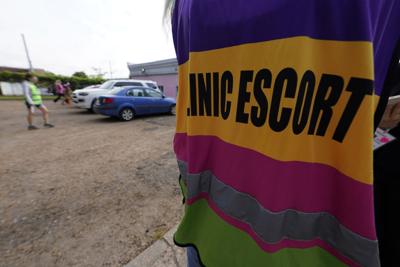 A clinic escort stands watch at the parking lot entrance while others escort a staff member to the Jackson Women's Health Organization, Mississippi's last remaining abortion clinic, on Tuesday.