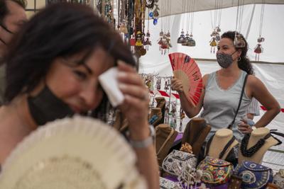 FILE - Women cool themselves with fans in the Rastro flea market during a heatwave in Madrid, Spain, Aug. 15, 2021. Scientists say last summer was the hottest summer on record in Europe, with temperatures a 1.8 Fahrenheit higher than the average for the...