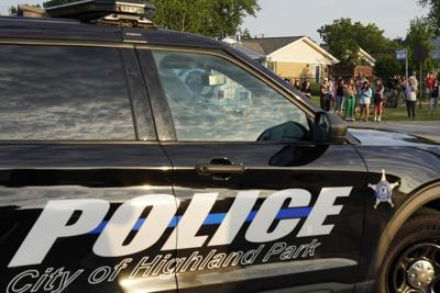 A police vehicle drives into the Highland Park police department as people look on following a mass shooting at the Highland Park Fourth of July parade in downtown Highland Park, a Chicago suburb, on Monday, July 4, 2022.