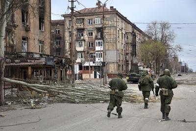 Servicemen of the militia from the Donetsk People's Republic walk past damaged apartment buildings in Mariupol, Ukraine on April 16, 2022