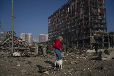 A woman walks with her dog amid the destruction caused after shelling of a shopping center, in Kyiv, Ukraine on March 21.