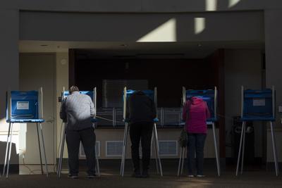 Three people vote inside the Troy Community Center on Nov. 3, 2020, in Troy, Mich.