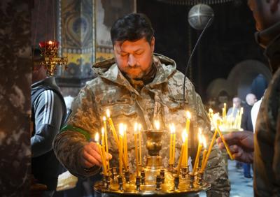 A Ukrainian soldier lights candles at the Volodymysky Cathedral during Easter celebration in Kyiv  on April 24, 2022.