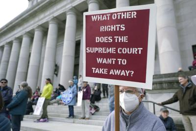 A person holds a sign as they take part in a rally in favor of abortion rights on the steps of the Temple of Justice, which houses the Washington state Supreme Court, Tuesday, May 3, 2022, at the Capitol in Olympia, Wash.