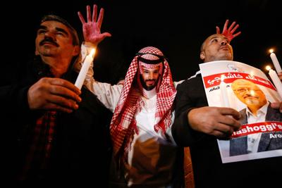 A protester wearing a mask depicting Saudi Crown Prince Mohammed bin Salman, holds up his hands, painted with fake blood, during a candlelight vigil in honor of Saudi journalist Jamal Khashoggi outside Saudi Arabia's consulate in Istanbul on Oct. 25, 2018.