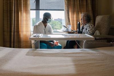 Caregiver Momah Walopaye talks with resident Joan Vogel at Goodwin House in Alexandria, Va. on July 6, 2022.
