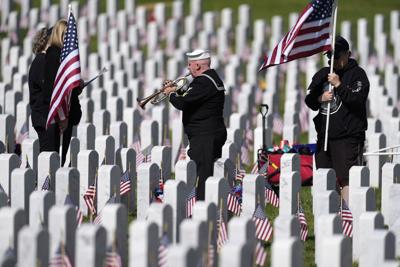 Retired U.S. Navy Yeoman First Class Mark Stallins plays Taps for the family of a fallen soldier at a graveside in Fort Logan National Cemetery on May 30, 2022, in Sheridan, Colo.