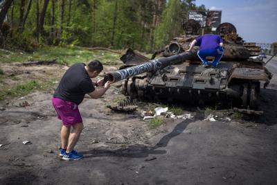 A man takes photos of a destroyed Russian tank, on the outskirts of Kyiv, Ukraine, on May 8, 2022.