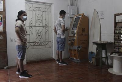 People use the first ATM designed to withdraw cash through the cryptocurrency app "Bitcoin Beach" in Tamanique, El Salvador on June 9, 2021.