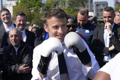 French President Emmanuel Macron wears boxing gloves as he campaigns April 21, 2022, in Saint-Denis, outside Paris.