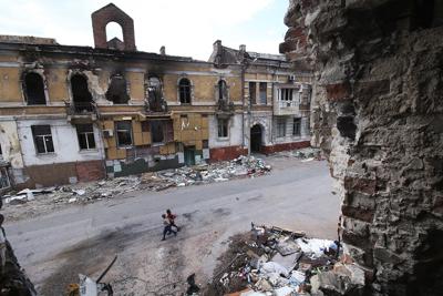 Children walk amid destroyed buildings in Mariupol in eastern Ukraine.