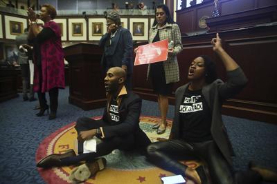 Rep. Tray McCurdy (D-Orlando) and Rep. Angie Nixon (D-Jacksonville) sit on the Florida Seal in protest on April 21 in Tallahassee, Fla.