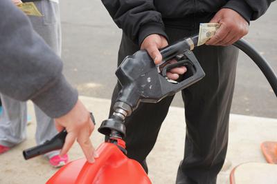 An attendant fills gas canisters as people wait in line at a Shell gas station in Matawan, N.J.