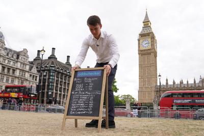 A man puts out a chalkboard in Parliament Square offering the the latest odds as to when Britain's Prime Minister Boris Johnson will leave his post and who will replace him  July 6, 2022.