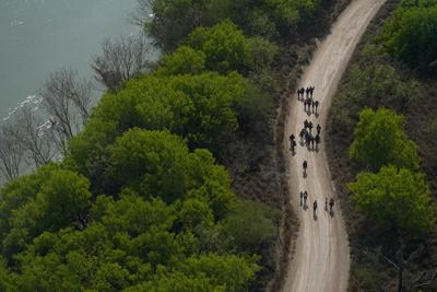 Migrants walk on a dirt road after crossing the U.S.-Mexico border on March 23, 2021, in Mission, Texas.