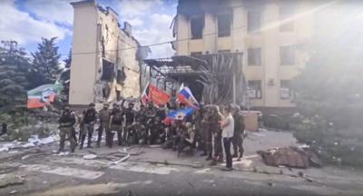 Russian troops, including soldiers of a Chechen regiment, wave Russian and Chechen flags as they pose in front of a destroyed building in Lysychansk, Ukraine, on July 2, 2022.