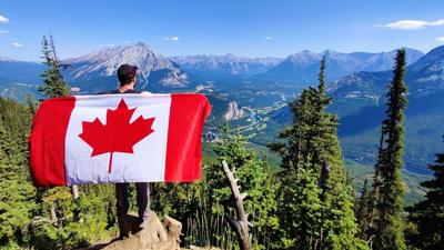A hiker holding a Canada flag over Banff Unsplash