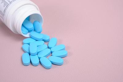Dispersión de píldoras azules de la botella sobre fondo rosa vista superior